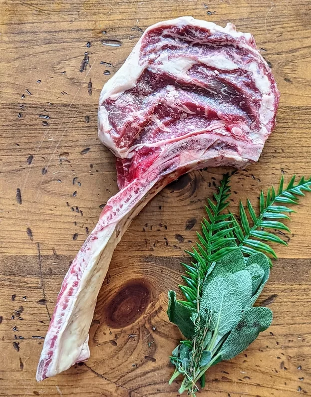 Wagyu tomahawk steak with the long frenched bone, herbs alongside