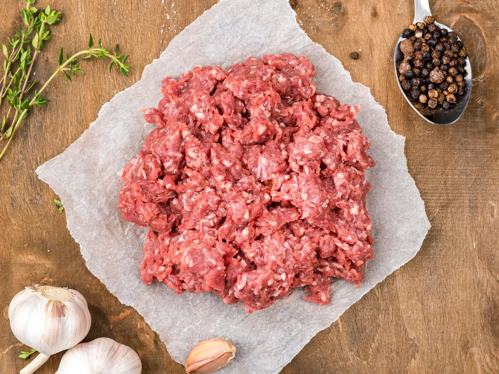 Ground Wagyu beef on butcher paper with garlic and peppercorns