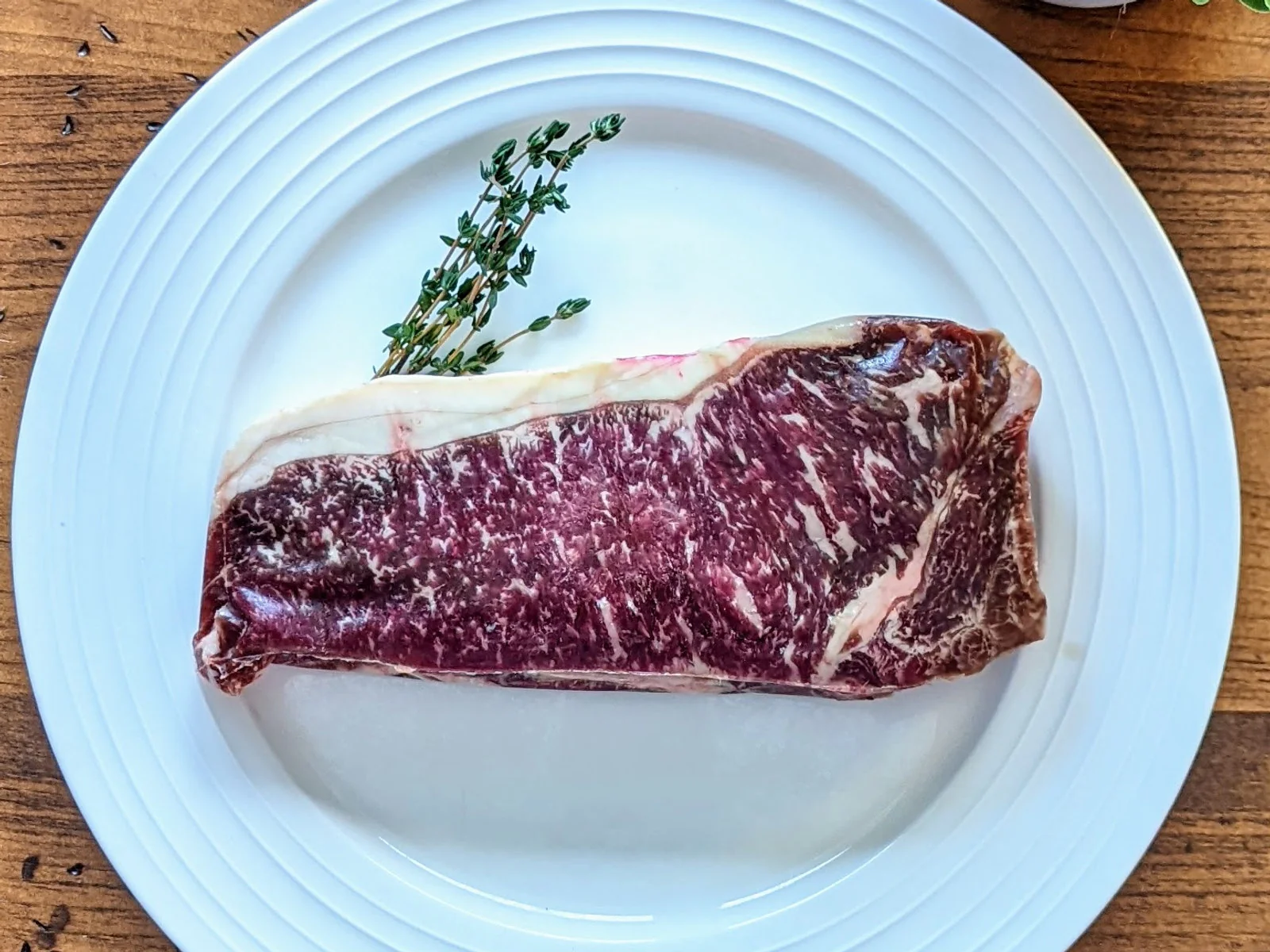 Three quarter inch Wagyu striploin steak plated with thyme